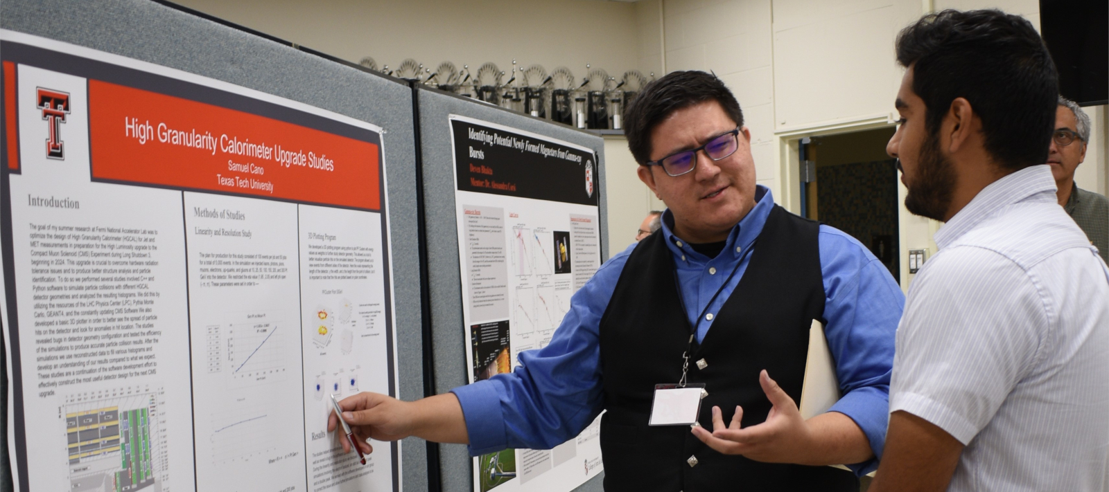 Michael Holcomb standing next to a student as he discusses the student's research poster